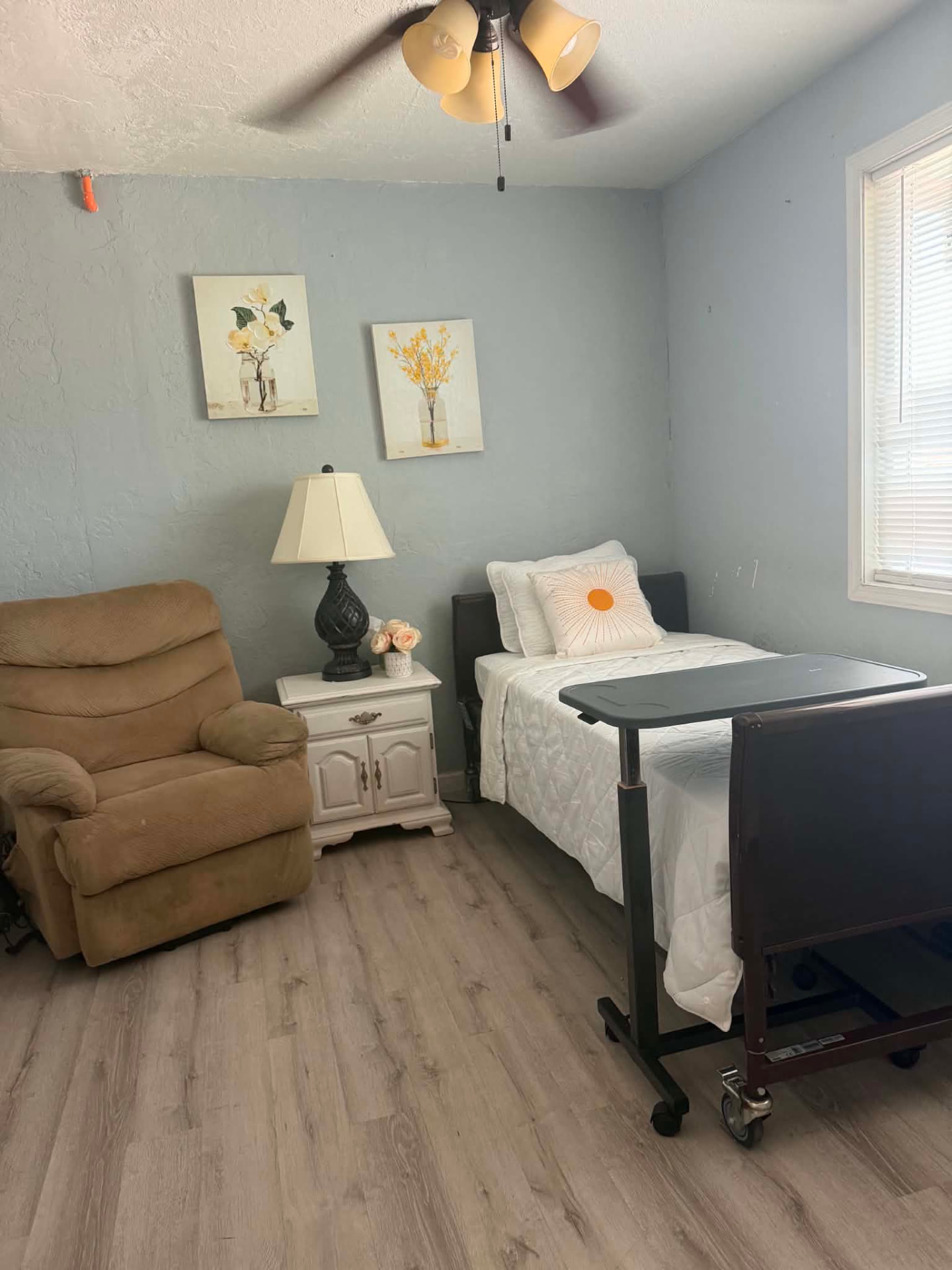 Resident bedroom with recliner, nightstand and overbed table